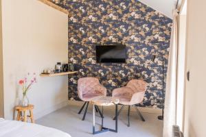 a bedroom with two pink chairs and a wall with a wallpaper at Boerderij 1811 in Harich