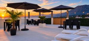 a patio with tables and chairs and umbrellas at Apartments and Studios Anicic in Utjeha