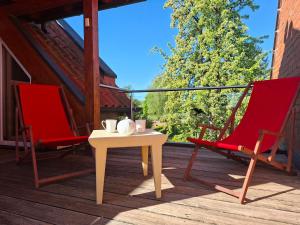 two red chairs and a table on a porch at Design Ferienhaus Kamerun an der Elbe in Damnatz