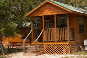 Medina Lake Camping Resort Cabin 3 في Lakehills: كابينة خشبية مع شرفة وسطح
