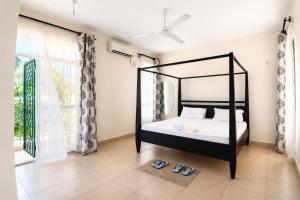 a bedroom with a black canopy bed and slippers at Ary Homestay Nyali At Pearl Residence 3rd Avenue Nyali, Mombasa, Kenya in Nyali +7 photos