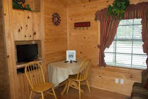 Medina Lake Camping Resort Cabin 3 في Lakehills: غرفة طعام مع طاولة وكراسي وتلفزيون