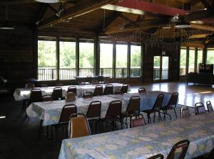 Habitación grande con mesas, sillas y ventanas. en Mount Vernon Camping Resort Studio Cabin 5, en Bow