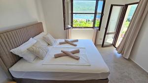 two towels on a bed in a room with windows at Villa Sava in Đenovići