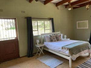 a bedroom with a white bed and two windows at Shamwari Guesthouse in Kalkheuvel