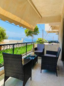 a patio with chairs and tables and an umbrella at Peaceful Seaside Apartments in Vaia