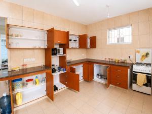a large kitchen with wooden cabinets and appliances at Ary Homestay Nyali At Pearl Residence 3rd Avenue Nyali, Mombasa, Kenya in Nyali