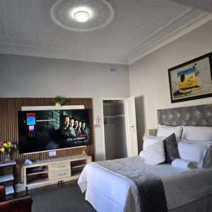 a bedroom with a bed and a flat screen tv at The Wentworth Guest House in Krugersdorp