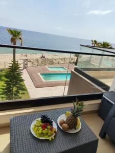 a table with two plates of fruit on a balcony at Beachfront Dream, WaveHaus in Akouda