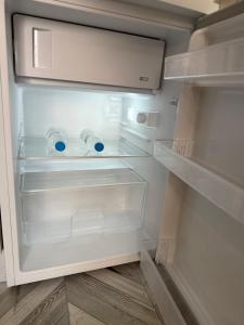 ein leerer Kühlschrank mit offener Tür und seinen Regalen in der Unterkunft Studio Lite Ermou#17 in Kateríni