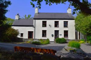 a white house with a bench in front of it at Hen Gamdda Fawr in Llanallgo