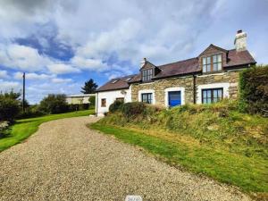 a stone house on a hill with a gravel road at Ysgol Hill Main House in Rosebush