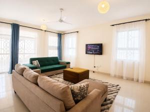 a living room with a couch and a tv at Ary Homestay Nyali At Pearl Residence 3rd Avenue Nyali, Mombasa, Kenya in Nyali