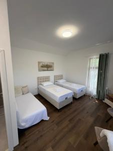 two beds in a room with white walls and wooden floors at Studio Kolo-M in Blagaj