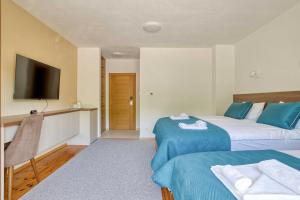 a hotel room with two beds and a flat screen tv at Milver Apartments Kolasin in Kolašin