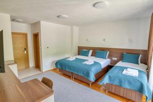 a room with two beds and a table and a tv at Milver Apartments Kolasin in Kolašin