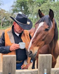 a man in a cowboy hat holding a cup next to a horse at Mama Adama, Alpaca Farm And B&B in Grândola