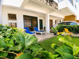 a house with a yard with blue chairs and a car at Ary Homestay Nyali At Pearl Residence 3rd Avenue Nyali, Mombasa, Kenya in Nyali