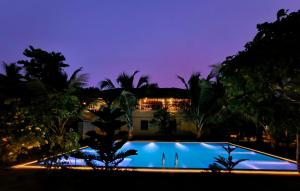 a swimming pool in front of a house at night at Gram Bangla Retreat in Kolkata