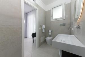 a bathroom with a sink and a toilet and a window at Sea View Hotel Fronte Mare in San Vito lo Capo