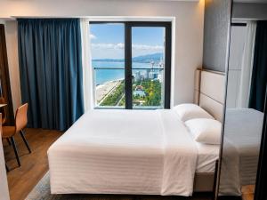 a hotel room with two beds and a large window at Signature Residence Sea View Suites in Marriott Privilege in Batumi