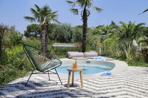 a patio with a chair and a table and a pool at Ekies All Senses Resort, a Member of Design Hotels in Vourvourou