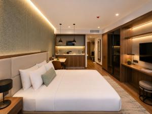 a bedroom with a large white bed and a kitchen at Signature Residence Sea View Suites in Marriott Privilege in Batumi