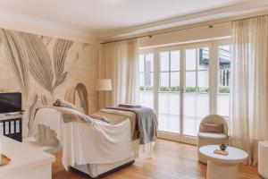 a bedroom with a bed and a large window at Parkhotel Egerner Höfe in Rottach-Egern