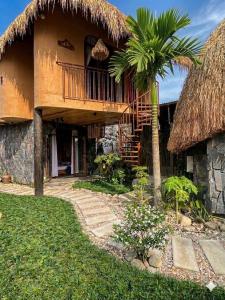 a house with a thatched roof and a palm tree at Tom Home Retreat in Mỹ Lại (1)