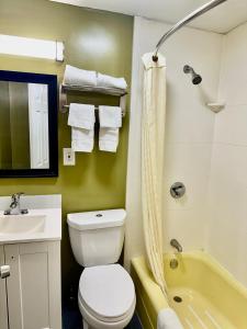 a bathroom with a toilet and a sink and a tub at Wickford Motor Inn in North Kingstown +22 photos