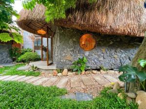 a stone building with a straw roof and a pathway at Tom Home Retreat in Mỹ Lại (1) +19 photos