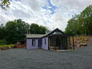 a small purple house sitting on top of a gravel driveway at Lakelands Cottage in Nenagh