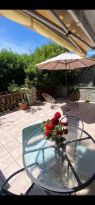 a glass table with flowers and an umbrella on a patio at Appartamento Catalina in Saint-Pierre