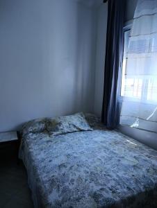 Una cama deshecha en un dormitorio con ventana. en Ouadlaw, en Oued Laou