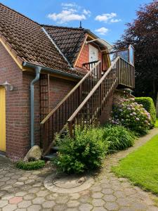 a brick house with a wooden staircase in a yard at Ferienwohnung Blumenthal bei Kiel in Blumenthal
