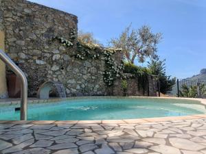 a swimming pool in front of a stone wall at La Cornice dei Monti in Tramonti
