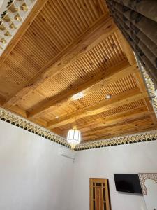 a room with a wooden ceiling with a tv on it at Khalid Boutique in Bukhara
