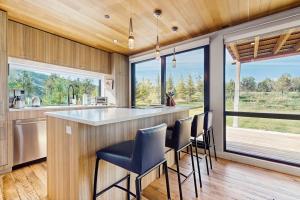 a kitchen with a bar with chairs and windows at Tree Farm Sanctuary in Basalt