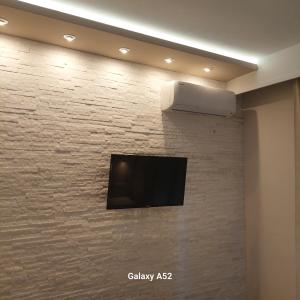 a flat screen tv on a brick wall at Apartment Natasha in Paralia Katerinis