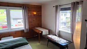 a room with two beds and a table and two windows at Grodås Lake View Apartment in Hornindal +4 photos