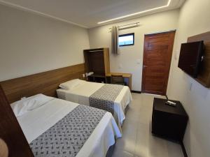 a hotel room with two beds and a television at NOVO HOTEL in Conceição do Coité