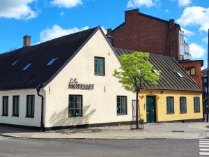 a white building with a black roof on a street at Lilla Hotellet in Lund