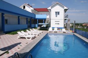 a swimming pool with lounge chairs and a house at Blue Lagoon in Costinesti