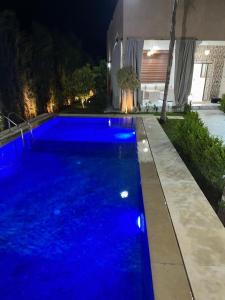 a blue swimming pool in a yard at night at villa privée ghmat in Marrakesh