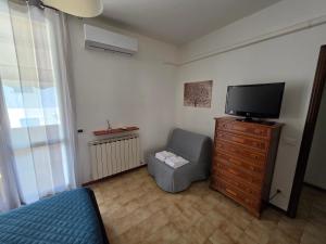 a bedroom with a tv and a chair and a dresser at Appartamento Pullino in Marina di Ravenna