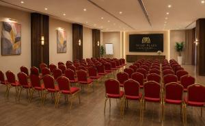 a conference room with red chairs and a screen at TULIP PLAZA - By Le Park Concord in Hafr Al-Batin
