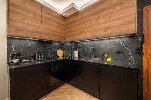 a kitchen with black counters and wooden cabinets at Apartament Bursztynowa Komnata 117 Stegna nad morzem in Stegna