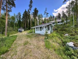 a small white house in the middle of a forest at Lake Cottage Onnenranta in Kolinkylä