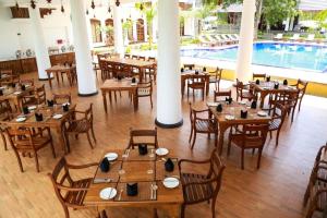 a restaurant with wooden tables and chairs and a pool at Peacock Wild YALA in Tissamaharama