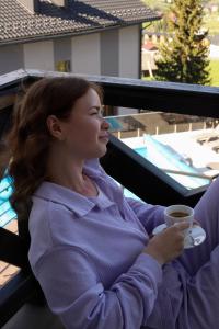 a woman sitting on a balcony with a cup of coffee at Князів Двір in Bukovel